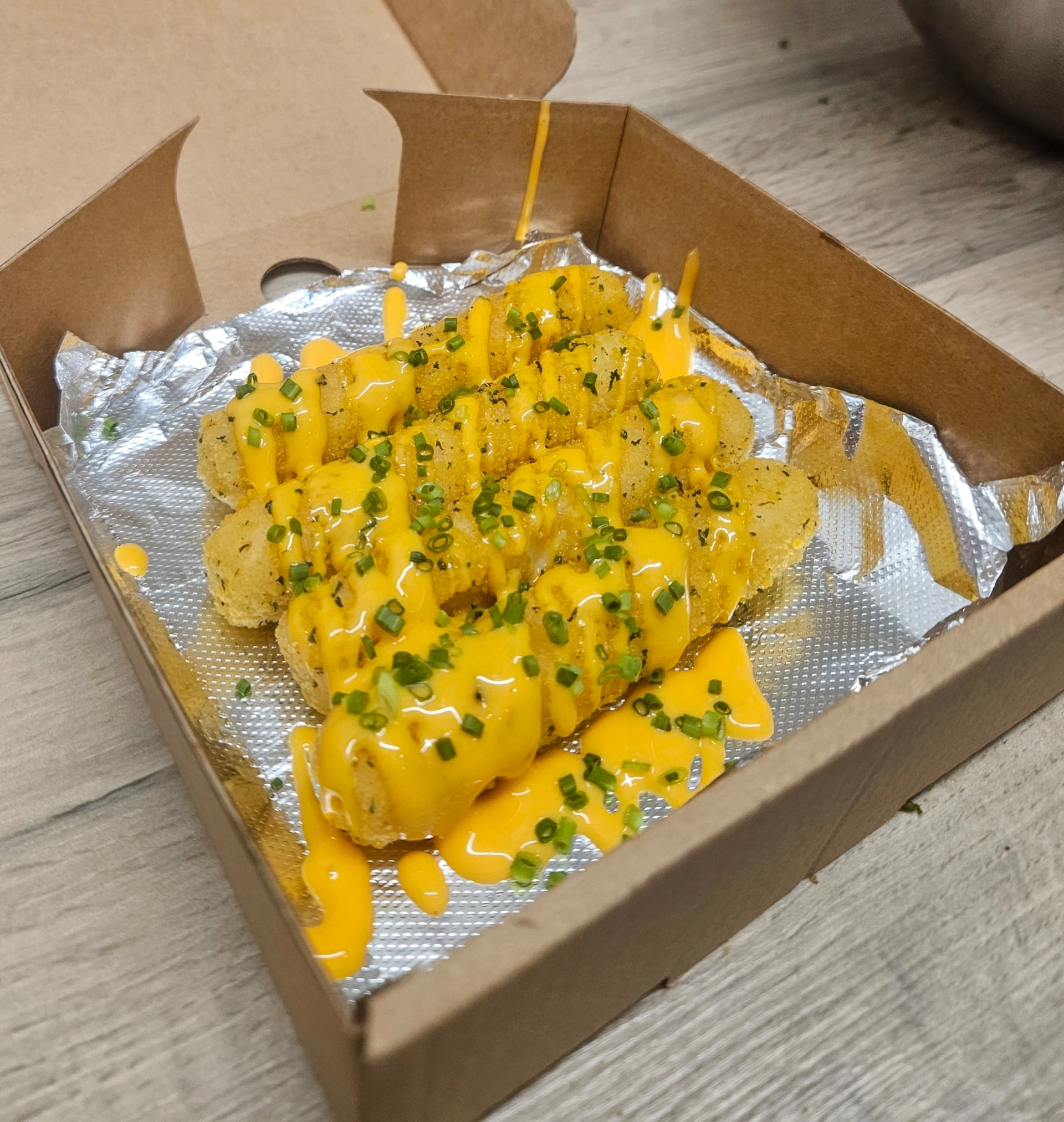 Mozzarella sticks topped with nacho cheese sauce and chives